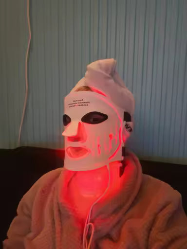 Person wearing the illuminated Flexible Red Light Face & Neck Mask while seated at home.