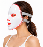 Side view of a woman wearing the illuminated Red Light Therapy Mask, showing its grey adjustable straps and clear frame