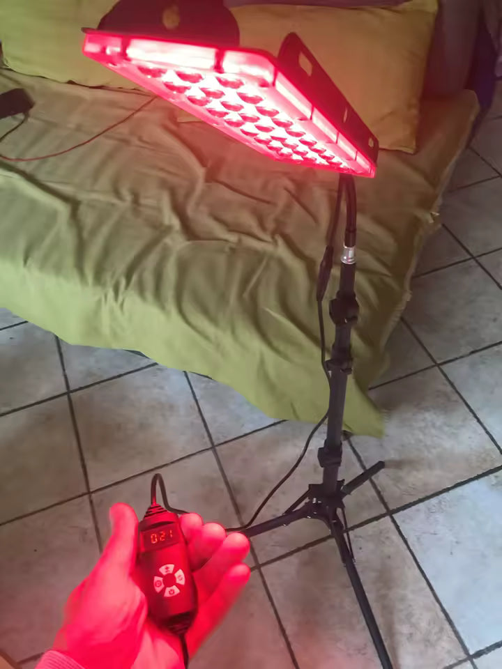 The illuminated panel on its tripod, with the wired controller in hand.