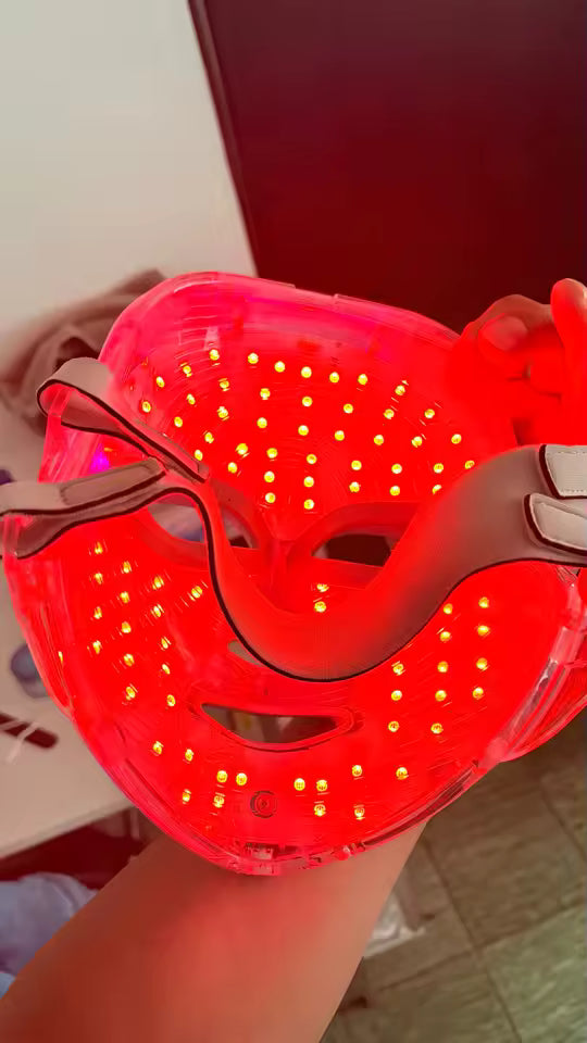 Customer holding the Red Light Therapy Mask to show the illuminated inner LEDs and straps.
