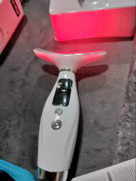 The handheld wand with its curved light head switched on.